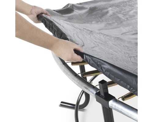 Person lägger ett trampolinskydd över en studsmatta