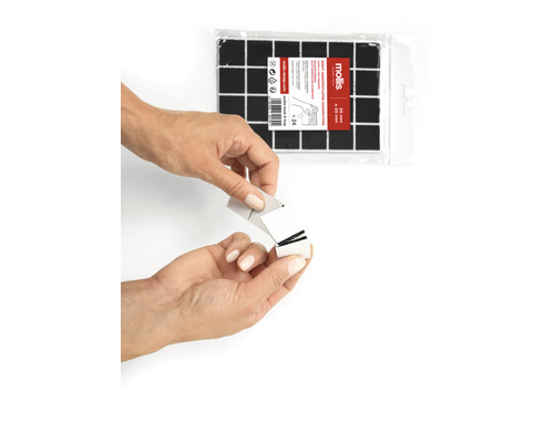 Fyrkantiga, självhäftande kuddar, 20 gånger 20 millimeter, i en förpackning med 24 stycken. En person tar bort skyddsfilmen från en kudde.