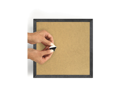 Person som fäster en självhäftande upphängning på en fotoramens baksida.