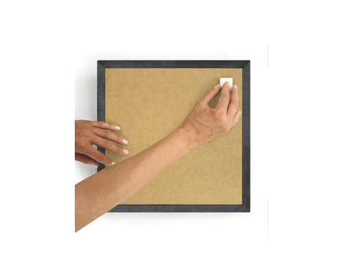 Person fäster en självhäftande remsa på en fotoram.