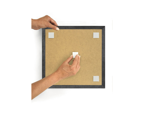 Person som fäster självhäftande kuddar på en fotoram