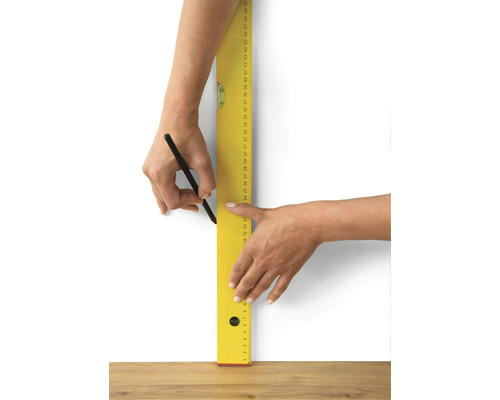 Person ritar en linje med penna och vattenpass på en vägg.