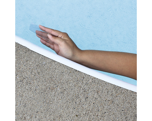 Hand berör poolvatten vid poolkanten