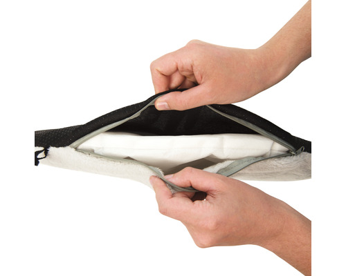 Händer öppnar dragkedjan på en hundbädd.