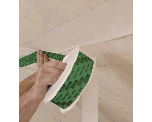 En person fäster tätningsband på en vägg