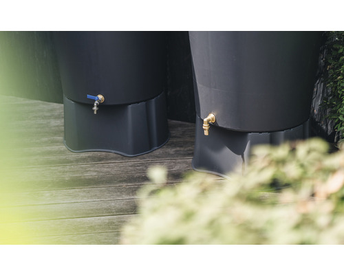 Närbild av två regnvattentunnor med kran på en träaltan