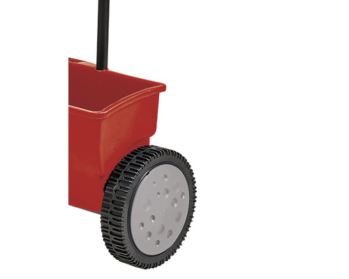 Detaljvy av en spridningsvagn med röd behållare och svart handtag