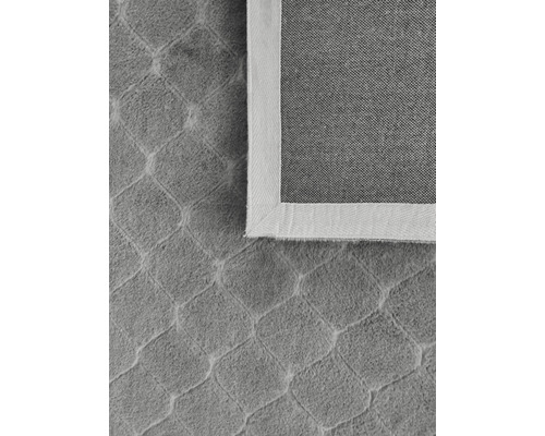 Detaljvy av en grå matta med geometriskt mönster och ljus kant