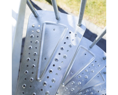 Detaljbild av metallisk spiraltrappa med steg med hål.