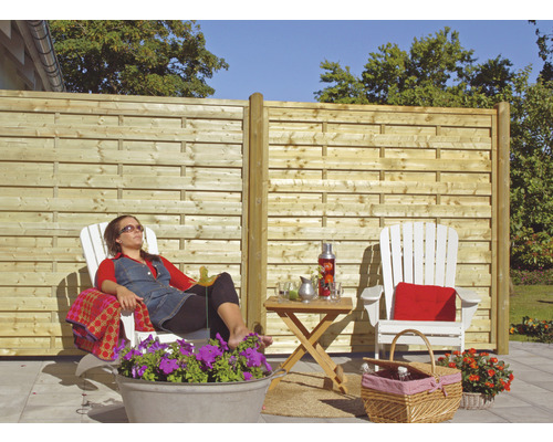 Trädgårdsscen med trästaket, trädgårdsmöbler och en avslappnad person