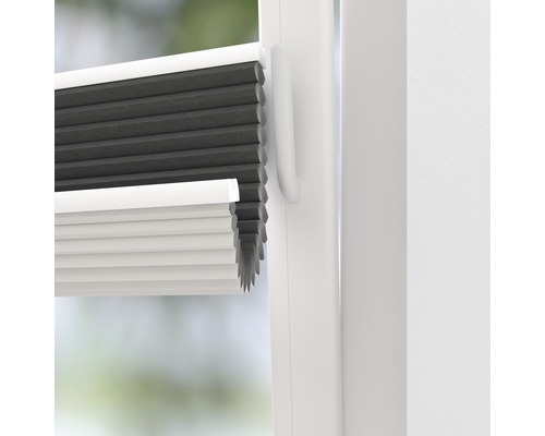 Närbild av en grå och vit plisségardin på fönstret