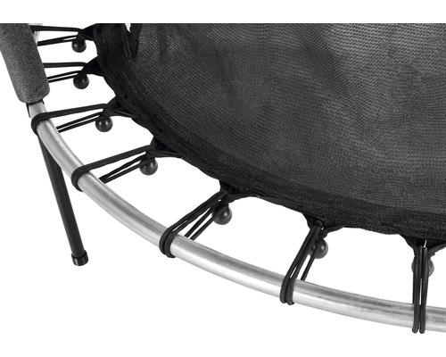 Detalj av en studsmatta med svart hoppduk, silverfärgad ram och elastiska band