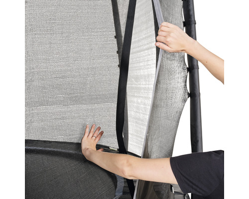 Detaljbild av ett trampolinsäkerhetsnät som är delvis öppet för att möjliggöra åtkomst.