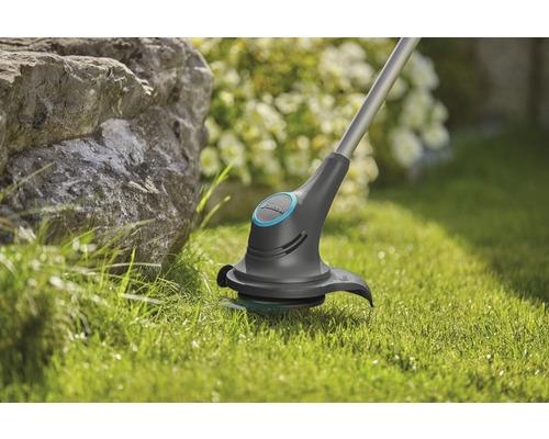Grästrimmer i drift på gräsmatta i trädgården.