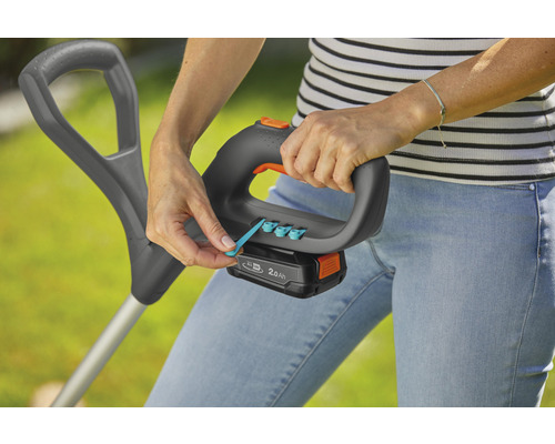 En kvinna använder en grästrimmer med batteri