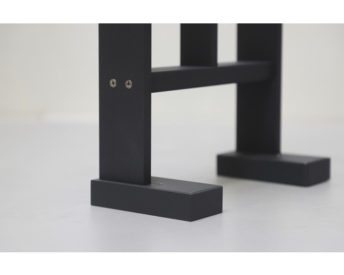 Detaljbild av en svart trähylla med skruvar