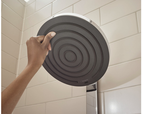 Person håller duschhuvud i badrum.