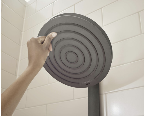 Hand berör ett runt duschhuvud i badrummet