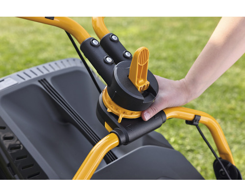 Detaljvy av en gräsklippare med en hand på handtaget för höjdjustering.