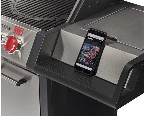 Detaljvy av en gasolgrill med smartphonehållare och Enders webbplats på skärmen