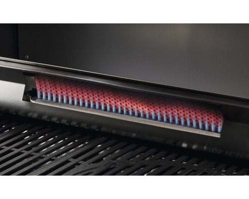 Detaljbild av en gasolgrillsbrännare i metall ovanför ett grillgaller