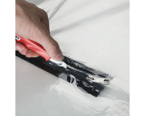 Närbild av en kniv som skär upp ett blixtlås