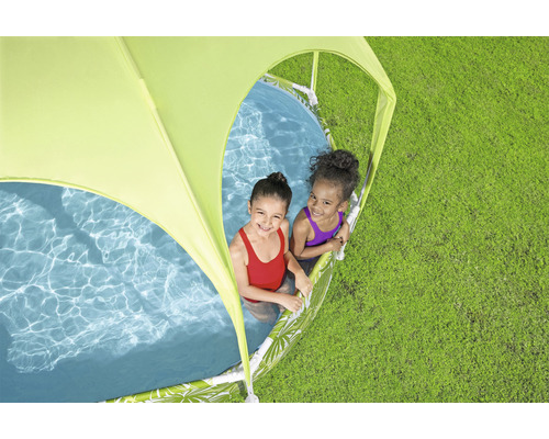 Två barn leker i en pool med solskydd på en gräsmatta.