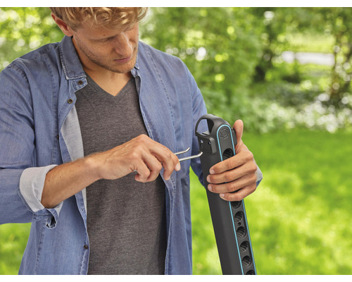 Man monterar en trädgårdsslangvagn med ett monteringsverktyg i trädgården.