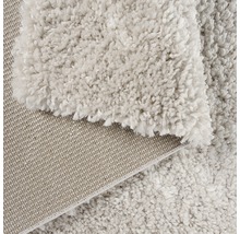 Detaljvy av en beige matta med hög lugg