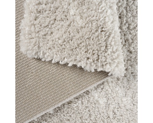 Detaljvy av en beige matta med hög lugg