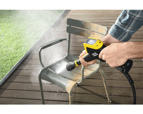 En person rengör en trädgårdsstol med en Kärcher högtryckstvätt.