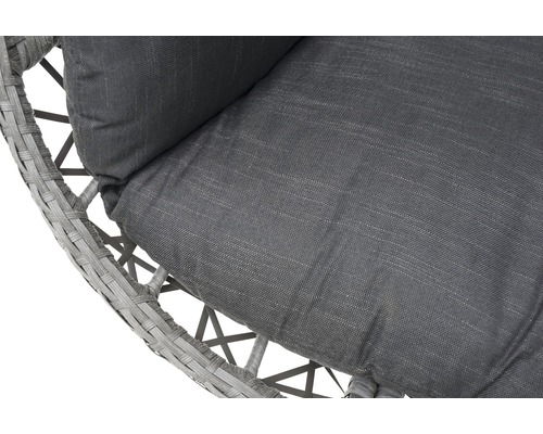 Närbild av en rottingfåtölj med grå kuddar