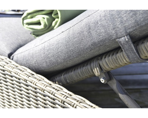 Närbild av en grå rottingfåtölj med klädsel och en grön duk