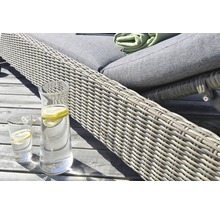 Närbild av en trädgårdsstol i rotting med en dryckkaraff och glas på ett träbord