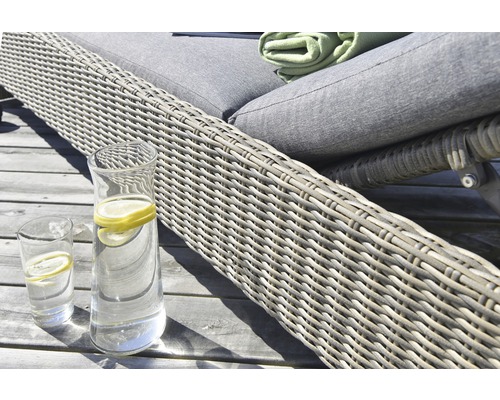 Närbild av en trädgårdsstol i rotting med en dryckkaraff och glas på ett träbord