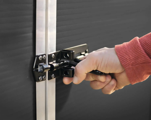 Hand som manövrerar ett dörrlås på en dörr