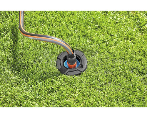 Bevattningsanslutningsbox med trädgårdsslang på gräsmatta