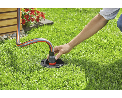 En person ansluter en trädgårdsslang till en vattenanslutning i trädgården