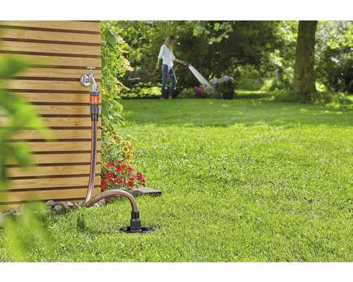 Trädgårdsscen med vattenkran, trädgårdsslang och grässprinkler för bevattning