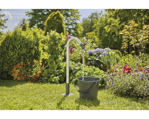 Trädgårdsscen med vattenkran och hink på gräsmatta