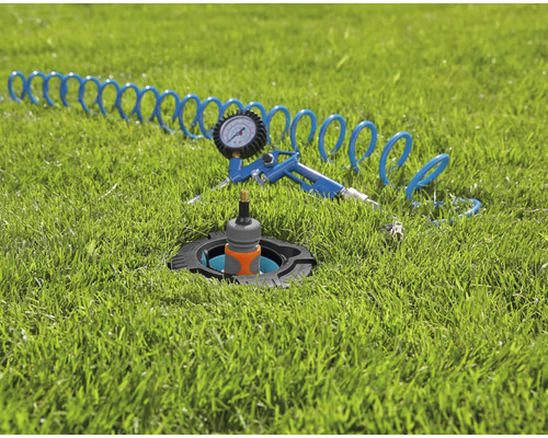 Pop-up-sprinkler med tryckluftpistol och slang på gräsmatta