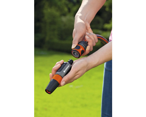 Händer ansluter Gardena slangkoppling med vattenstopp