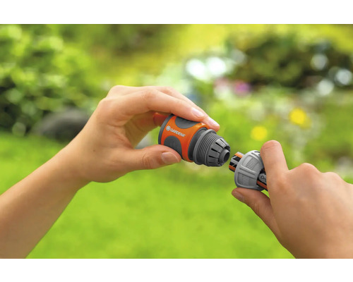 Två händer kopplar ihop två Gardena slangkopplingar.