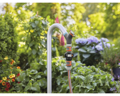 Trädgårdsscen med kran, slang och digital vattenmätare i trädgården