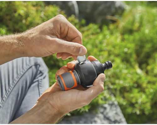 En person sätter in ett mynt i en trädgårdsvattentimer.