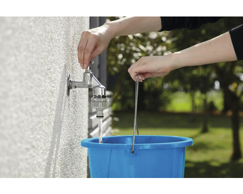 En person fyller en blå hink med vatten från en utomhuskran.