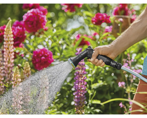 En person vattnar en trädgård med en trädgårdsspruta.