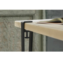 Detaljvy av ett bordsfäste med skruvtvinge på en bordsskiva och en bok som ligger på den.