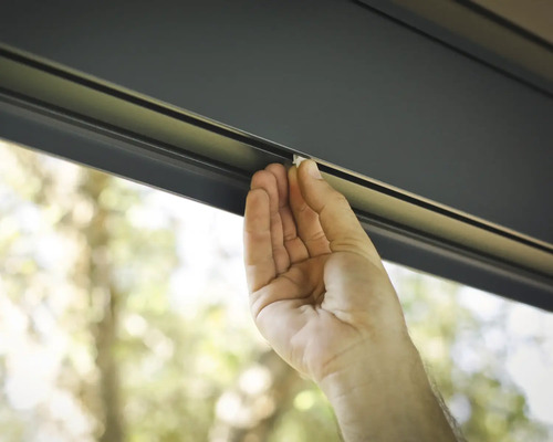 En hand skjuter in en liten vit del i en styrskena.