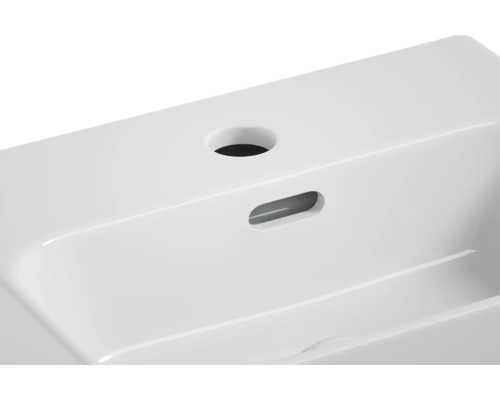 Detaljvy av ett vitt tvättställ i keramik med blandarhål och bräddavlopp